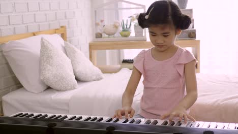 4K:-Asian-kid-girl-is-training-to-play-an-electric-piano.-Is-an-activity-that-trains-emotional-skills-And-the-body-well-Study-at-home-or-music-school-Music.-good-mental-health-and-good-mood.