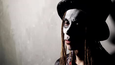 Portrait-of-man-with-scary-Halloween-makeup-in-black-hat-and-dreads-hairs