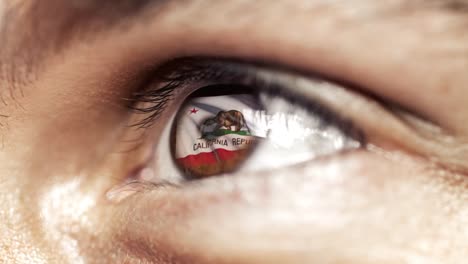 Hombre-con-el-ojo-marrón-de-cerca,-la-bandera-del-estado-de-California-en-iris,-estados-unidos-de-América-con-movimiento-de-viento.-concepto-de-vídeo