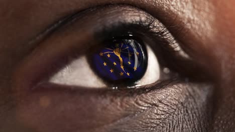 Woman-black-eye-in-close-up-with-the-flag-of-Indiana-state-in-iris,-united-states-of-america-with-wind-motion.-video-concept