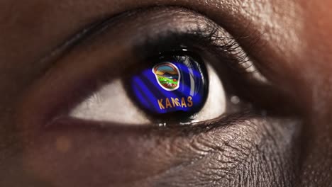 Woman-black-eye-in-close-up-with-the-flag-of-Kansas-state-in-iris,-united-states-of-america-with-wind-motion.-video-concept