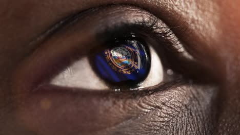 Woman-black-eye-in-close-up-with-the-flag-of-New-Hampshire-state-in-iris,-united-states-of-america-with-wind-motion.-video-concept