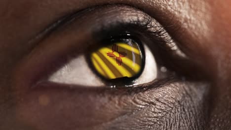 Woman-black-eye-in-close-up-with-the-flag-of-New-Mexico-state-in-iris,-united-states-of-america-with-wind-motion.-video-concept