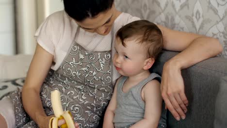 Baby-eats-banana-with-mother's-help