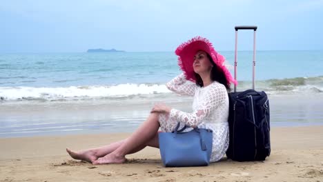 Girl-seats-on-the-beach-with-her-bagage-and-look