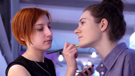 Concepto-de-belleza-y-moda.-Maquilladora-profesional-aplicarse-cosméticos-en-el-rostro-de-la-modelo.-Closeup