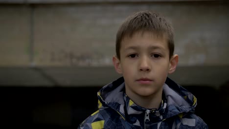 Boy-in-a-jacket-is-standing-on-the-street-serious-looking-at-the-camera-close-up