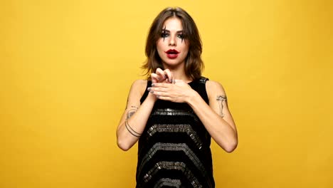 Young-strange-woman-with-creepy-make-up-showing-focus-with-finger-and-laughing-isolated-over-yellow-background