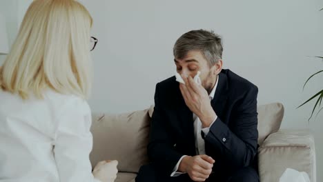 Female-psychologist-giving-paper-napkin-to-crying-businessman-patient-and-calm-him-down-in-her-office