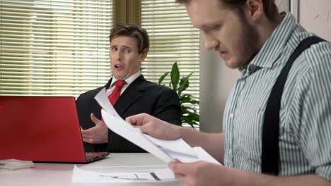 A-young-worker-makes-funny-faces-while-the-boss-does-not-see.-Parodizes-his-superior.-Work-in-the-office.-60-fps