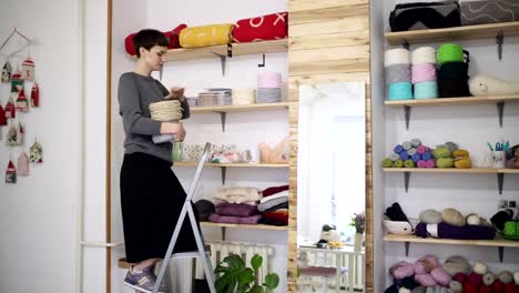 Creative-woman-shelving-thread-spool-on-stillage-in-textile-workshop