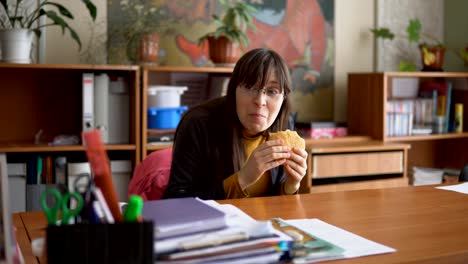 A-young-woman-in-glasses-tries-to-eat-hamburger-imperceptibly.