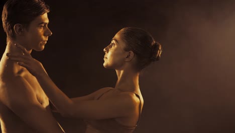 Primer-plano-retrato-de-bailarina-de-ballet-joven-hermoso-con-el-brillo-de-piel-de-oro-sobre-fondo-negro.-Arte-del-cuerpo-con-pintura-de-oro.-Bailarina-en-tutú-bailando-en-el-escenario-de-humo.-Cámara-lenta