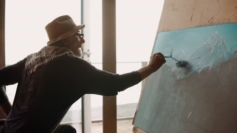 cute-retiree-in-a-hat-is-engaged-in-drawing-a-mountain-landscape-in-retirement