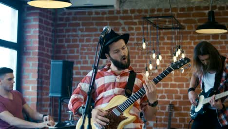 Emocional-barbudo-guitarrista-cantando-con-micrófono