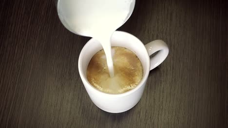 Preparation-process-of-coffee-with-shaked-up-milk---latte-or-cappuccino-in-white-cup.-Closeup-view