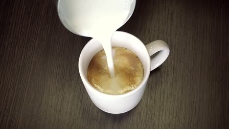 Zubereitung-von-Kaffee-mit-shaked-oben-Milch---Latte-oder-Cappuccino-in-weiße-Tasse.-Detailansicht