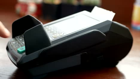 4K-footage.-man-holding-credit-card-in-hand-,-swipe-card-at-credit-card-terminal-reader-machine-and-use-finger-press-password-for-security-for-purchase-or-shopping-at-shop