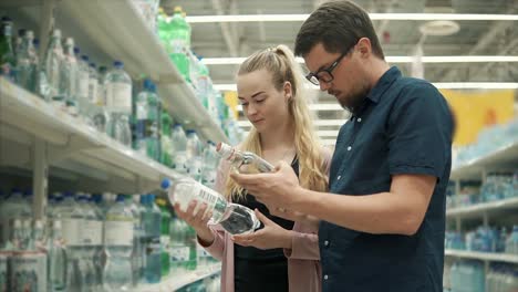 Ehegatten-sind-Etiketten-auf-Flaschen-mit-Wasser-in-einem-Geschäft-lesen.