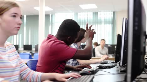 Teacher-Helping-Male-High-School-Student-Working-In-Computer-Class