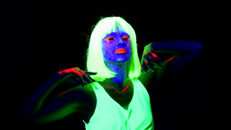Woman-with-UV-face-paint,-wig,-glowing-clothing-dancing-in-front-of-camera,-shoulder-shot.-Caucasian-woman.-.