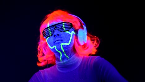 Slow-motin-of-Woman-with-UV-cyborg-face-paint,-wig,-glowing-glasses,-clothing-dancing-and-listening-to-music-with-headphones.-Asian-woman.-.