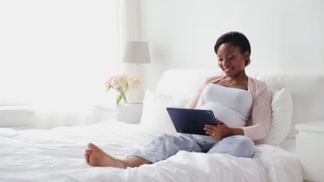 happy-pregnant-woman-with-tablet-pc-in-bed