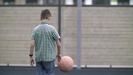 niño-está-entrenando-para-jugar-al-baloncesto,-al-aire-libre