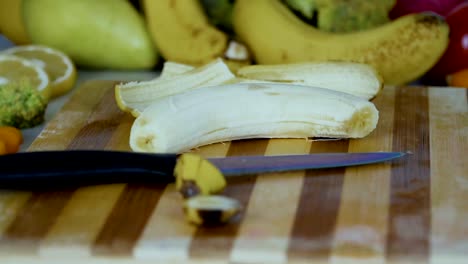 Man-setzt-eine-geschälte-Banane-auf-dem-Schneidebrett-in-Zeitlupe