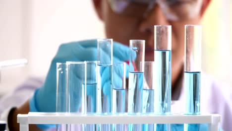 Close-up-of-scientist-hand-with-dropping-liquid-to-test-tube