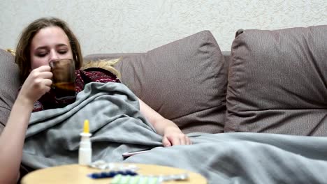 Teengirl-Medizin-Tee-warm-trinken.-Mit-einem-Smartphone-liegen-auf-der-couch