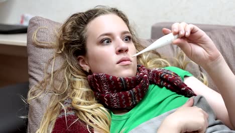 Teenager-Mädchen-misst-ihre-Temperatur,-verärgert-schaut-das-Fieberthermometer