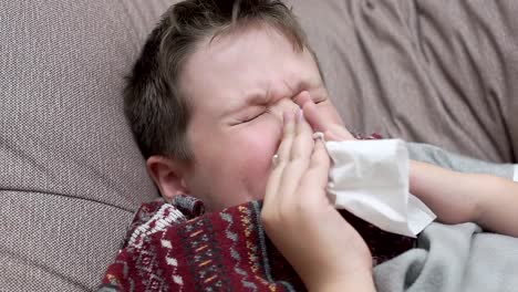 The-boy-blows-his-nose-in-paper-napkins.-He's-got-a-cold
