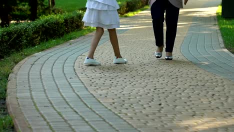 Handicapped-little-child-going-for-walk-with-elder-nurse-near-medical-clinic