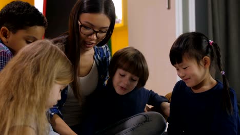 Teacher-with-kids-reading-a-book-in-kindergarten