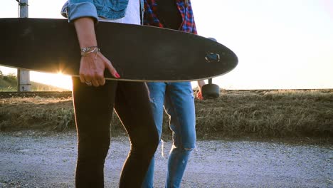 zwei-schöne-und-junge-Frauen-gehen-und-sprechen-mit-skateboard