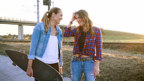 dos-mujeres-hermosas-y-jóvenes-caminando-y-hablando-con-patín