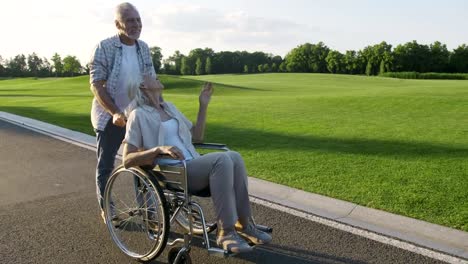 Senior-pareja-con-mujer-en-silla-de-ruedas-en-un-paseo