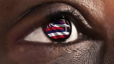 Woman-black-eye-in-close-up-with-the-flag-of-Hawai-state-in-iris,-united-states-of-america-with-wind-motion.-video-concept