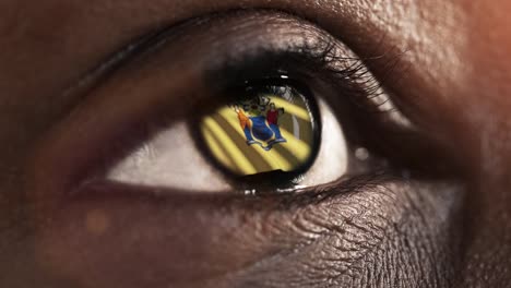 Woman-black-eye-in-close-up-with-the-flag-of-New-Jersey-state-in-iris,-united-states-of-america-with-wind-motion.-video-concept