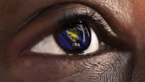 Woman-black-eye-in-close-up-with-the-flag-of-Oregon-state-in-iris,-united-states-of-america-with-wind-motion.-video-concept