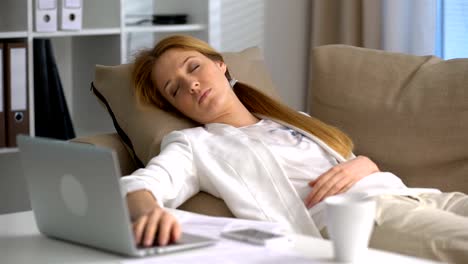 Tired-businesswoman-sleeping-on-the-couch-in-the-office-with-laptop-and-phone