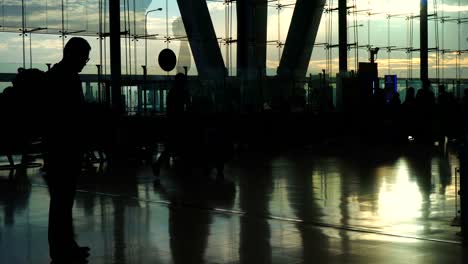 Masse-der-Menschen-Silhouette-zu-Fuß-Kontrast-mit-Morgen-Sonne-Licht-Glasarchitektur-am-Flughafen