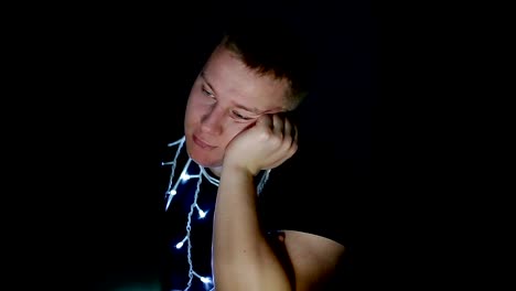 Sad-young-man-with-christmas-garland-using-computer