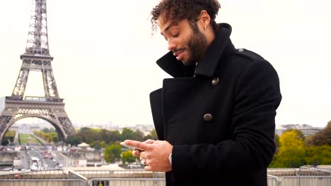 Novio-extranjeros-chat-con-chica-francesa-en-smartphone-alrededor-de-torre-de-Eiffel-en-cámara-lenta