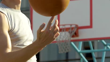 Muscular-caucasian-athlete-masterfully-spinning-basketball-on-his-finger,-trick