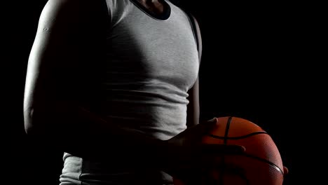 Skillful-basketball-player-holding-ball-in-muscular-hands,-ready-to-win-match