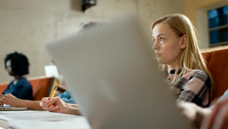 In-die-Klassenzimmer-Multi-ethnischen-Studenten,-Verwendung-Laptops-während-der-Wiedergabe-als-Dozent.-Einige-schreiben-in-Notebooks.-Helle-Jugendliche-Studium-an-der-Universität.