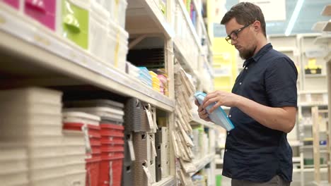 Erwachsener-Mann-mit-Brille-ist-in-einem-Supermarkt-neue-Kunststoff-Container-öffnen.