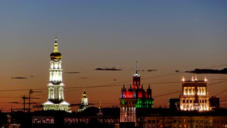 The-bell-tower-of-the-Assumption-Cathedral-Uspenskiy-Sobor,-City-council-and-house-with-a-spire-night-timelapse-in-Kharkiv,-Ukraine